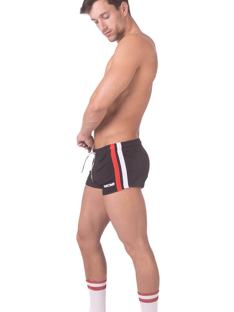 A model wearing black short-legged shorts with sporty side stripes and a drawstring waist.
