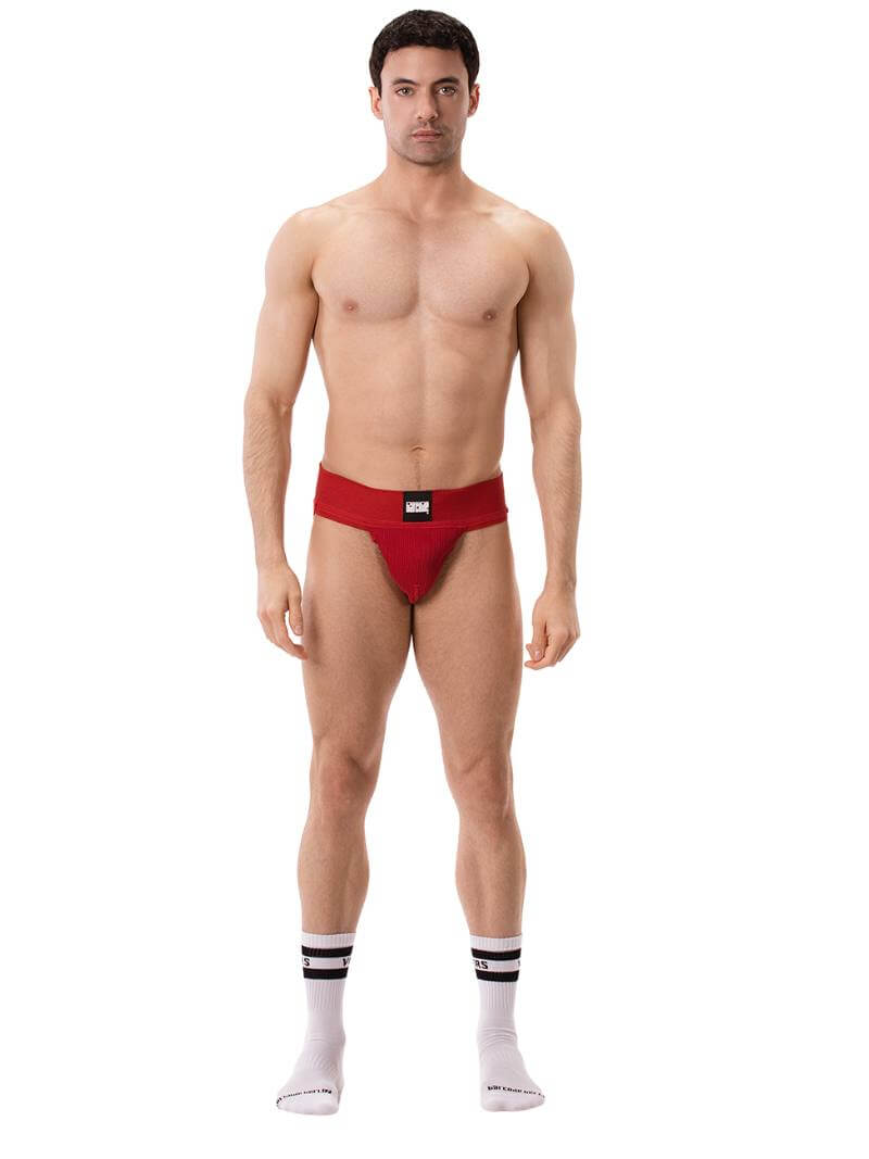 A model wearing a white Barcode Berlin Sergey ribbed cotton jockstrap, with the brand label visible on the waistband.