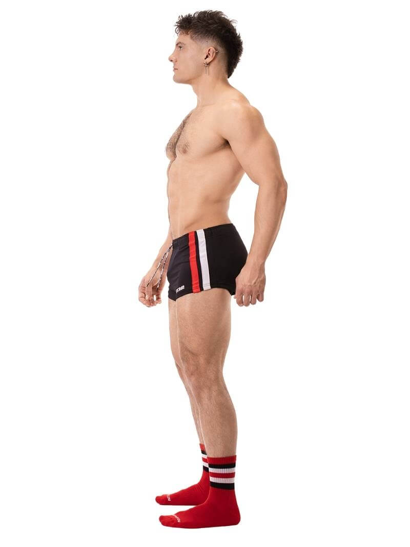 A model wearing black short-legged shorts with sporty side stripes and a drawstring waist.