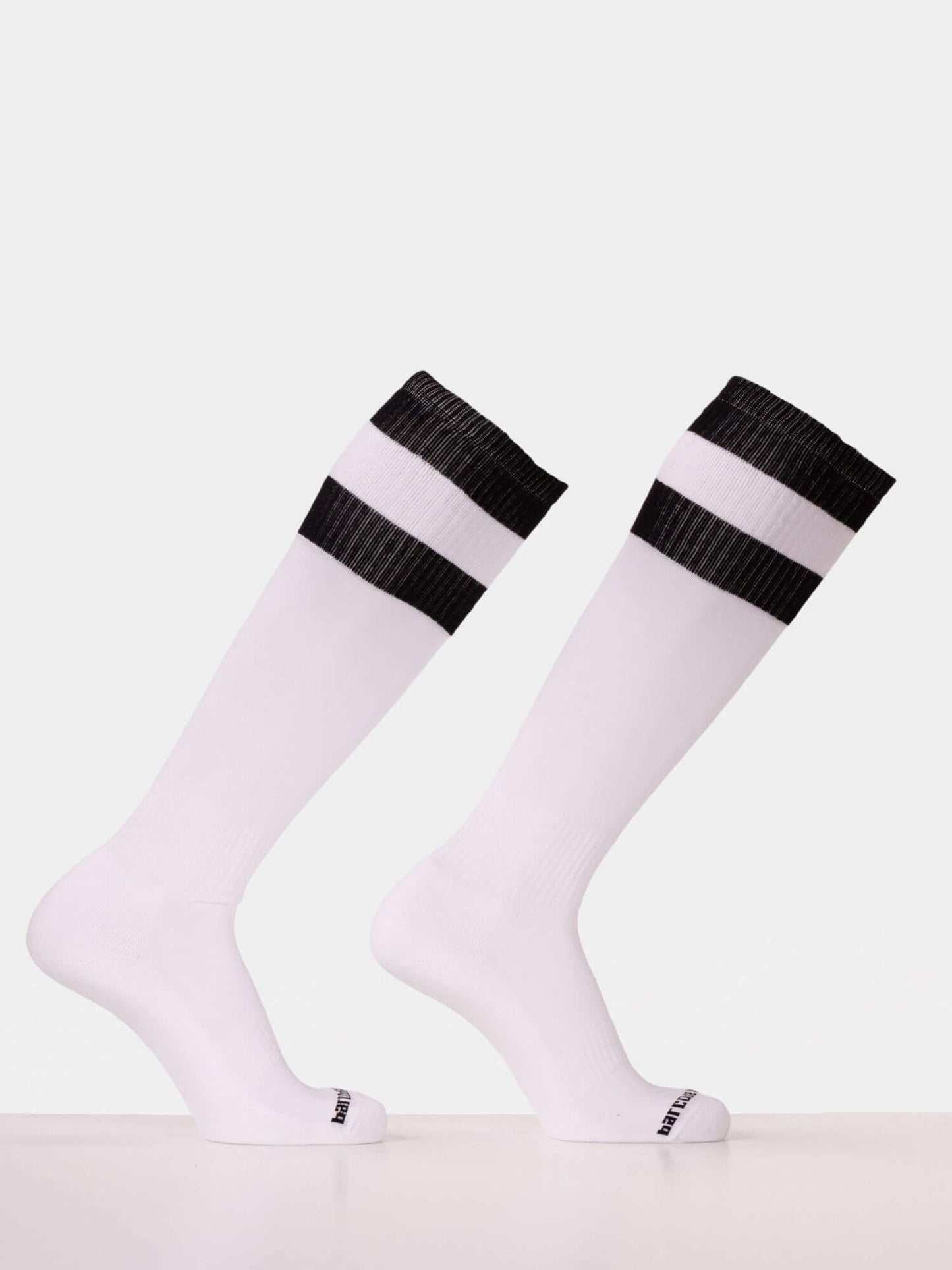 A pair of white knee-high athletic socks with two black horizontal stripes near the ribbed cuffs, displayed on invisible forms against a light gray background.