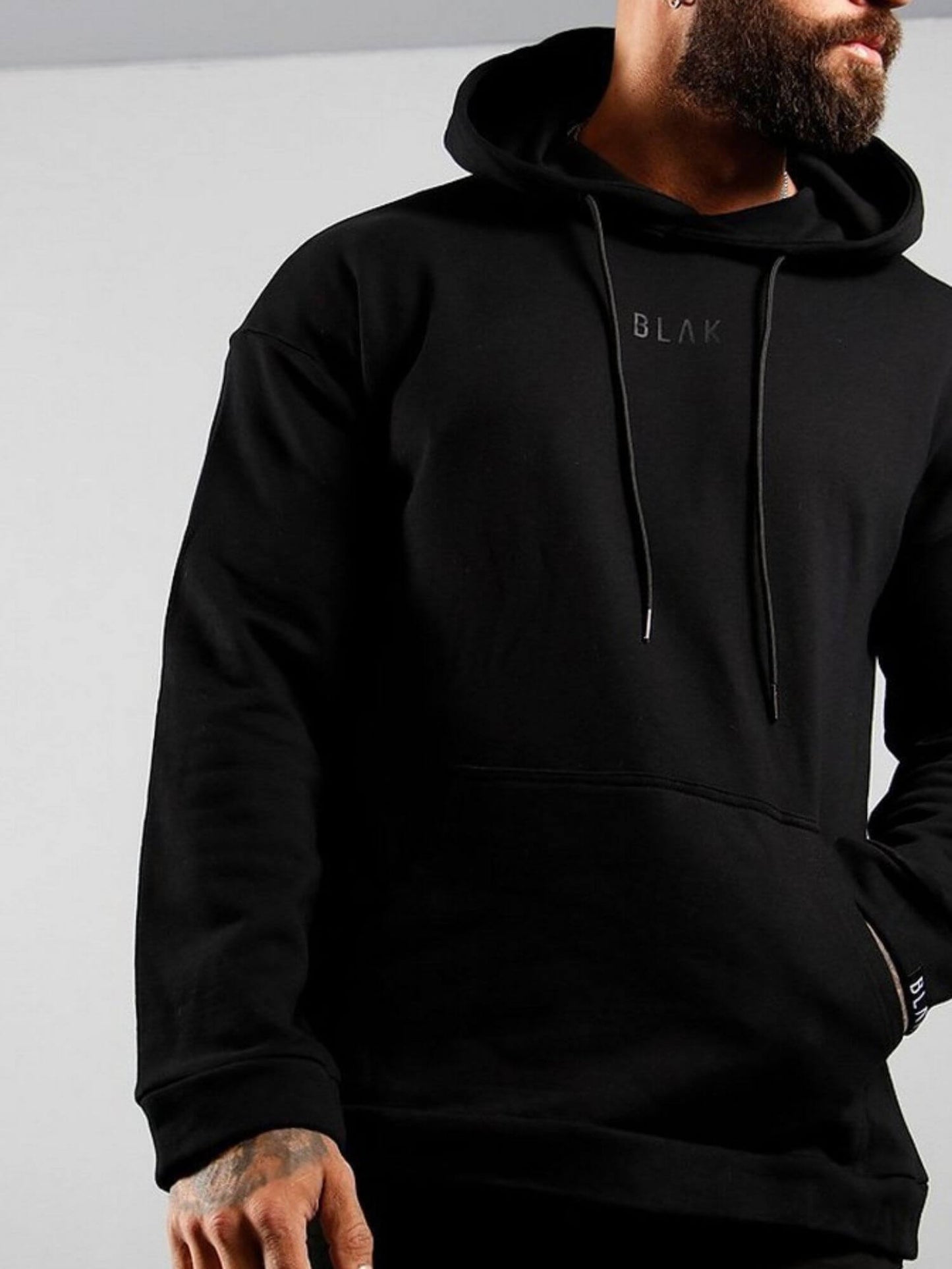 Person wearing a black hoodie with 'BLAK' branding on a gray background