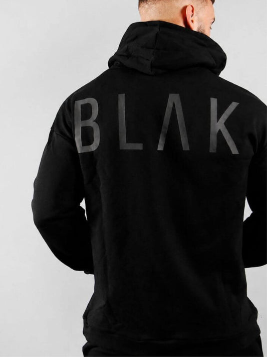 Person wearing a black hoodie with 'BLAK' branding on the back against a gray background