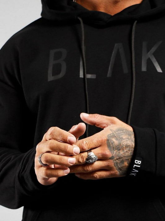 Person wearing a black hoodie with 'BLK' branding, showing tattooed hands.