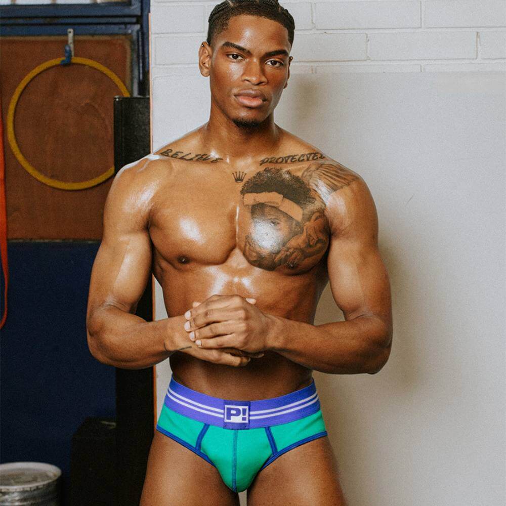 Man wearing green and blue underwear with a visible brand logo, standing against a neutral background.