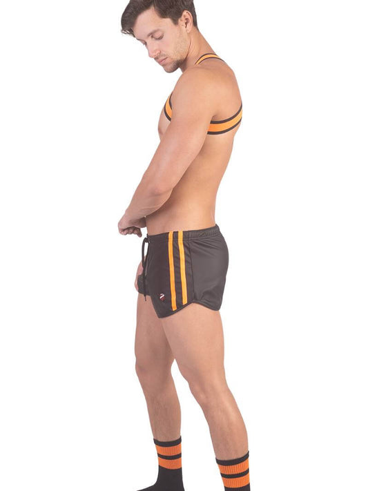 A man wearing red fishnet long-sleeve top and black mini shorts with sporty stripes and a drawstring.