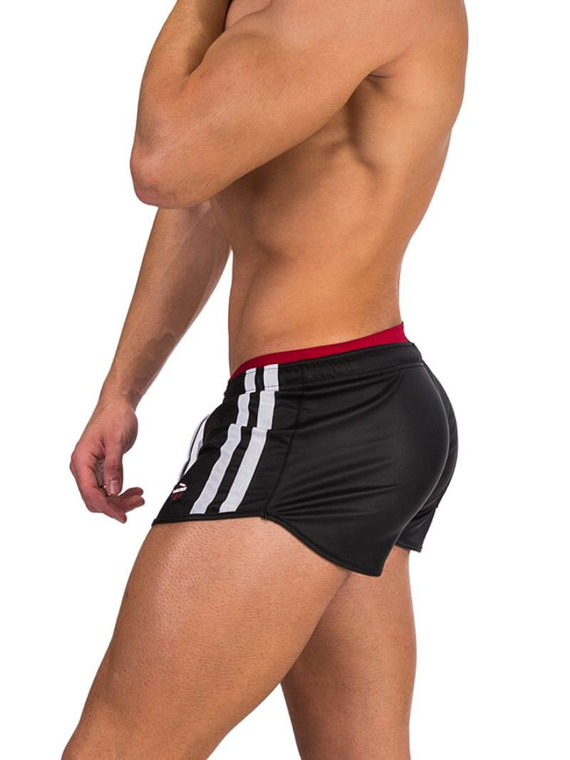 A man wearing red fishnet long-sleeve top and black mini shorts with sporty stripes and a drawstring.