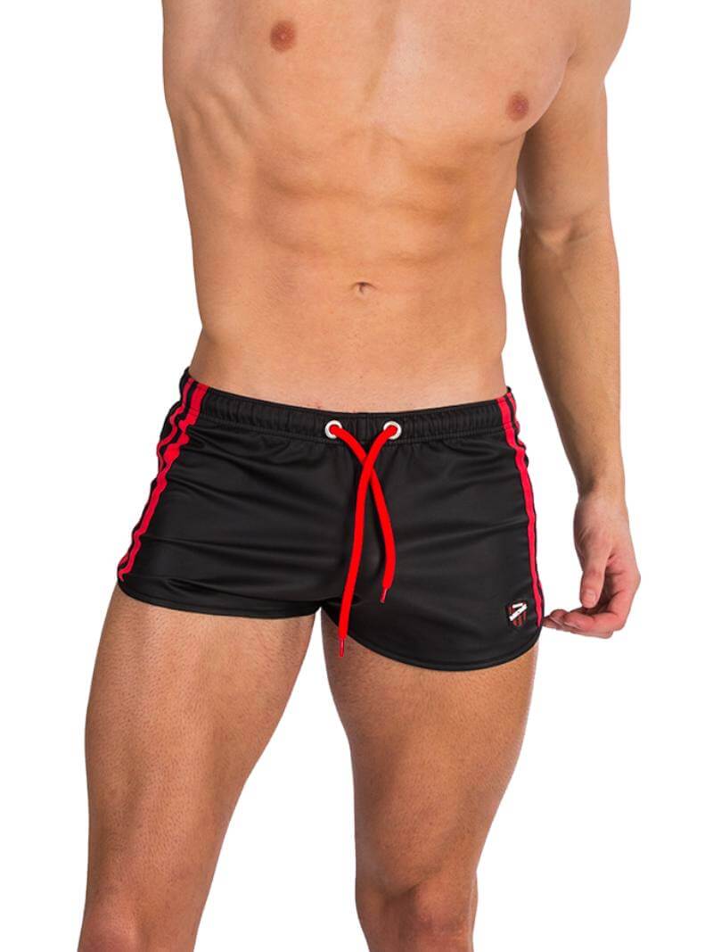 A man wearing red fishnet long-sleeve top and black mini shorts with sporty stripes and a drawstring.