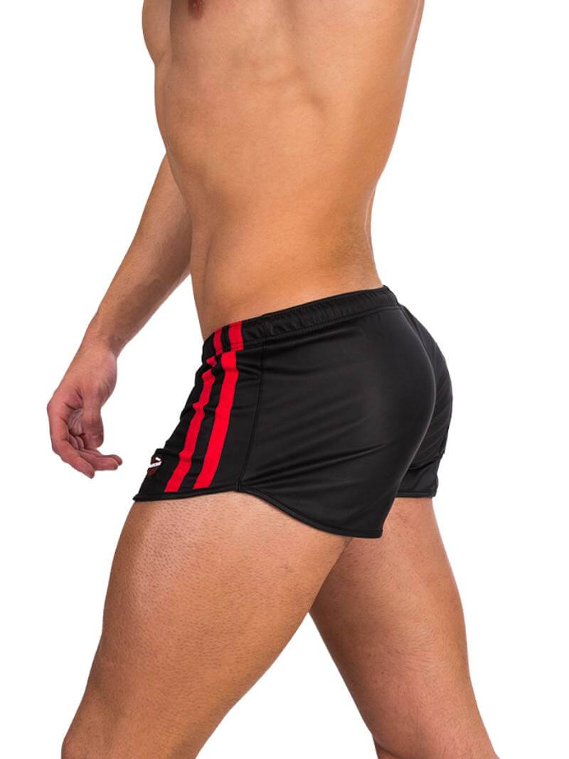 A man wearing red fishnet long-sleeve top and black mini shorts with sporty stripes and a drawstring.