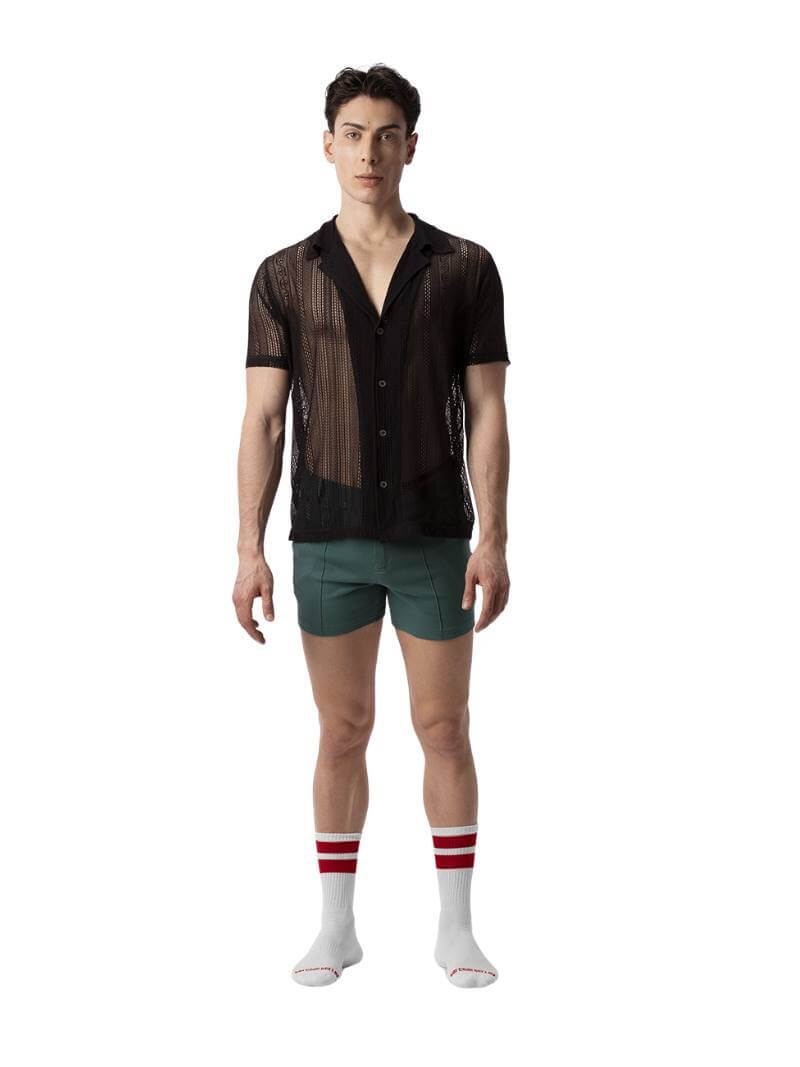 A male model wearing a black, semi-see-through lace shirt with short sleeves and a collared neck.