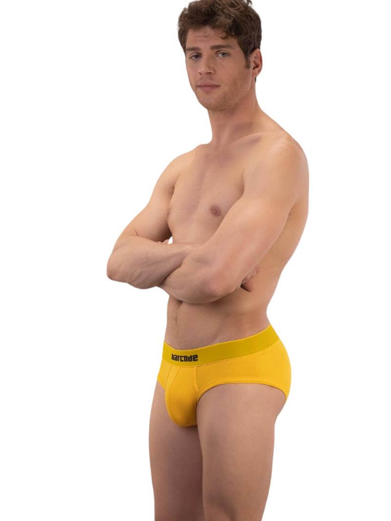 A model wearing a yellow cotton Barcode Berlin Helios backless brief with the brand's logo on the waistband.