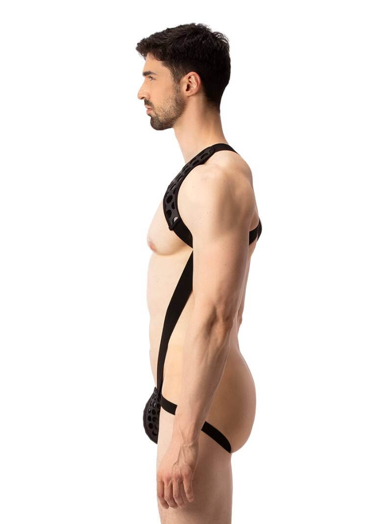 A model wearing a black and white polka dot body harness with a matching jockstrap. The harness features a chest panel, X-style back, and soft elastic straps.