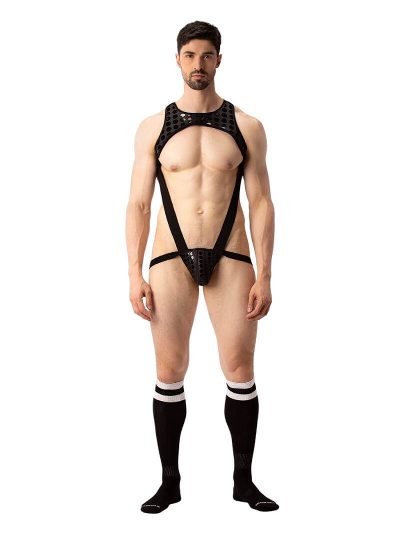 A model wearing a black and white polka dot body harness with a matching jockstrap. The harness features a chest panel, X-style back, and soft elastic straps.