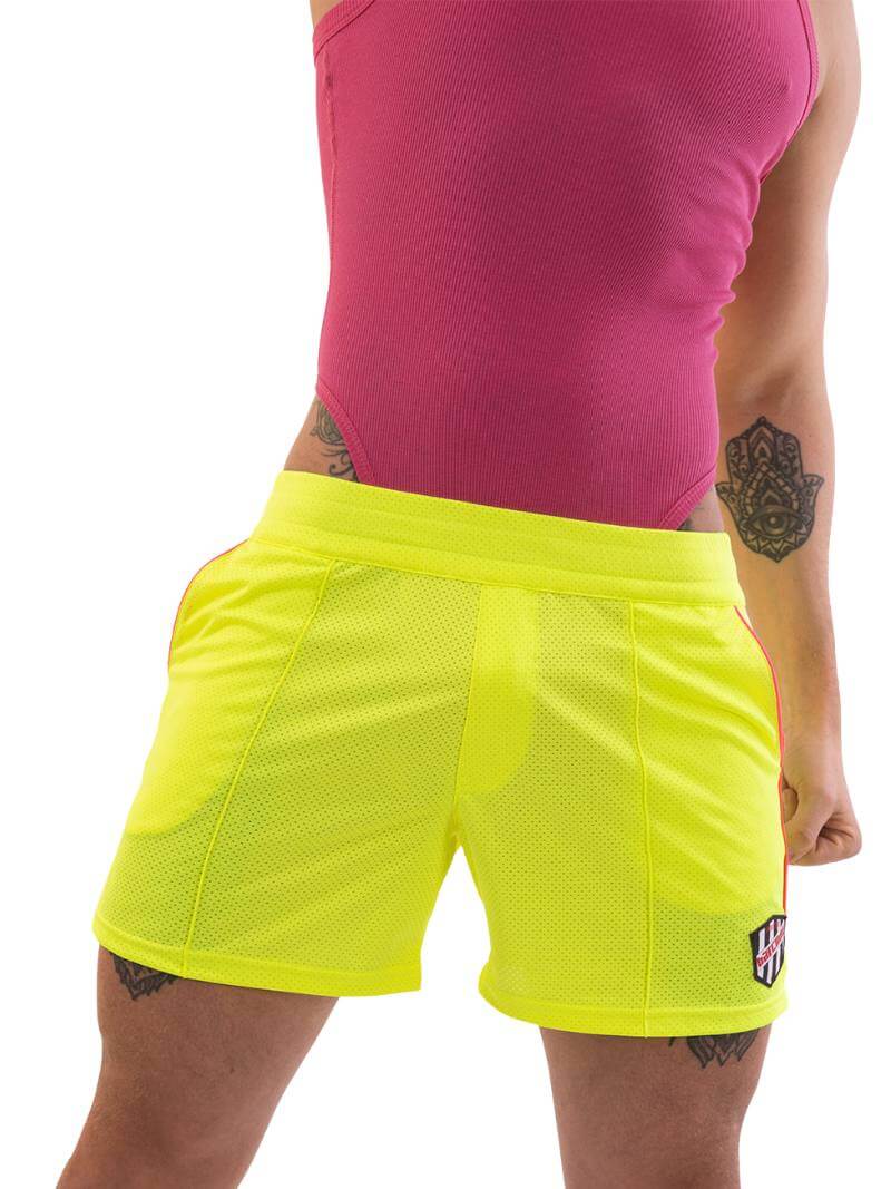 A model wearing olive green shorts with a black and white striped label and a pink top.