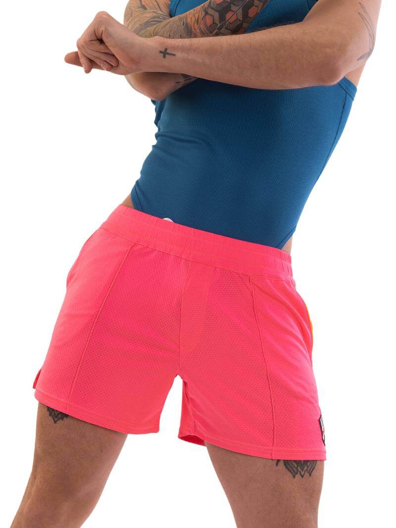 A model wearing neon pink shorts with striped label and a blue top.