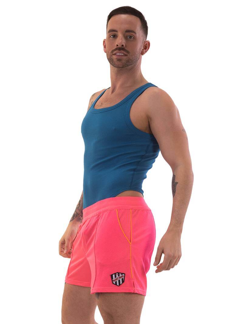 A model wearing neon pink shorts with striped label and a blue top.