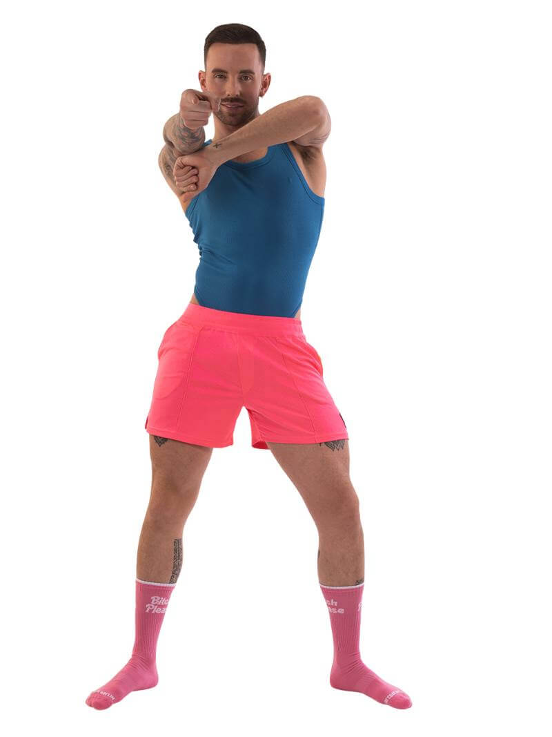 A model wearing neon pink shorts with striped label and a blue top.