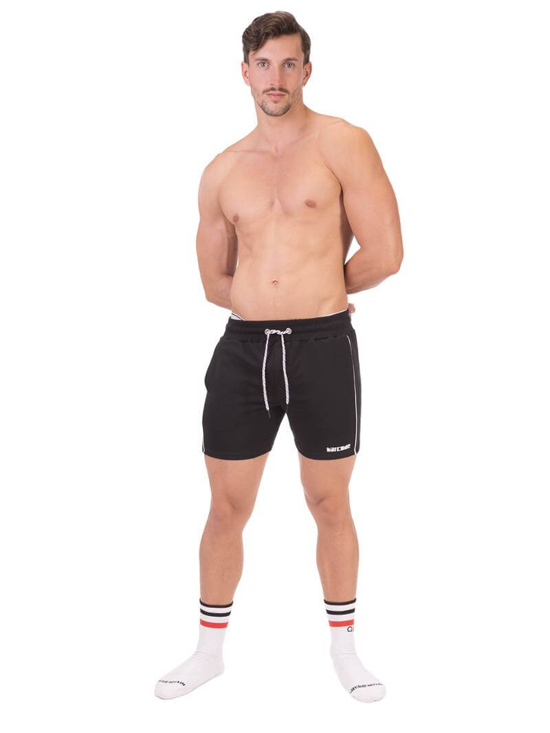 A person wearing black Barcode Berlin Lukio shorts with white trim stripes and a patterned drawstring.