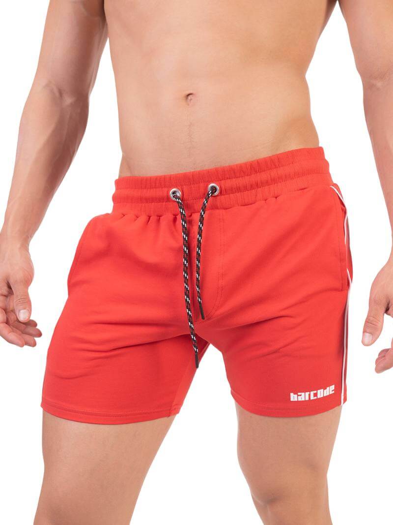 A person wearing red Barcode Berlin Lukio shorts with white trim stripes and a patterned drawstring.