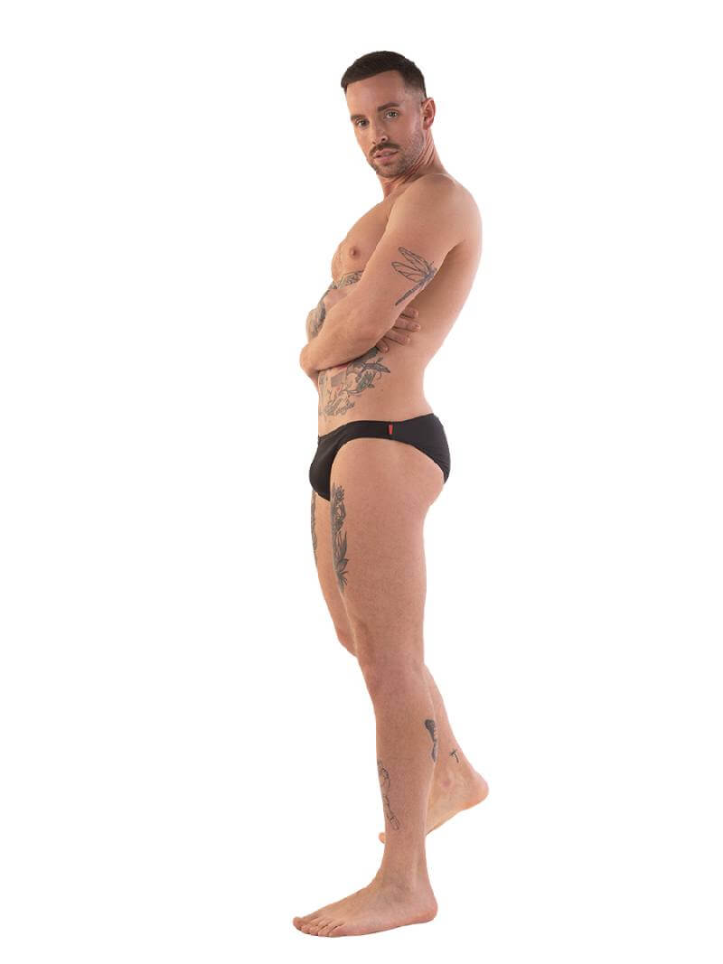 A person wearing red micro swimwear with a geometric pattern and the Barcode Berlin brand logo on the waistband.