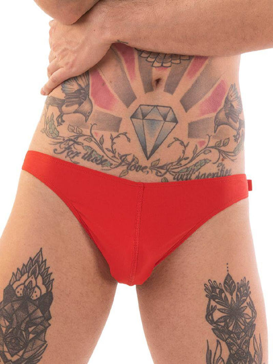 A person wearing red micro swimwear with a geometric pattern and the Barcode Berlin brand logo on the waistband.