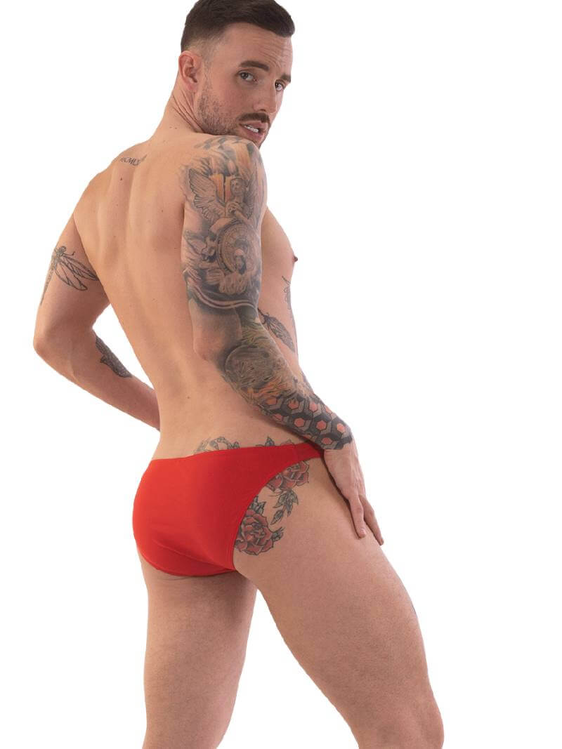 A person wearing red micro swimwear with a geometric pattern and the Barcode Berlin brand logo on the waistband.