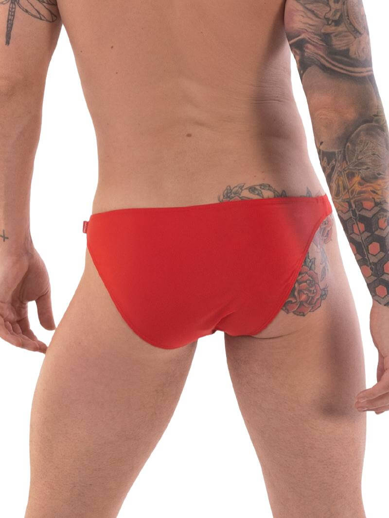 A person wearing red micro swimwear with a geometric pattern and the Barcode Berlin brand logo on the waistband.