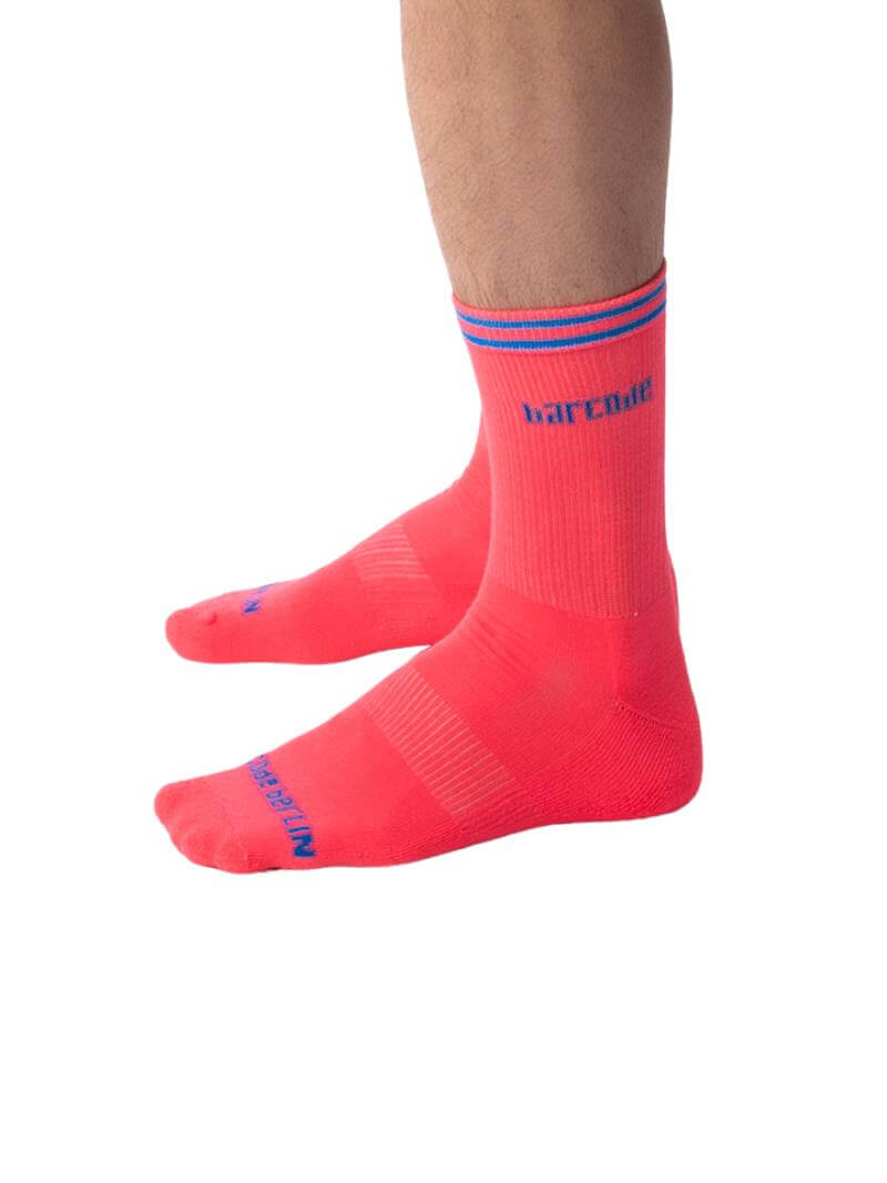 A pair of bright orange Barcode Berlin festival socks with contrasting pink and yellow stripes and the brand name on the side.