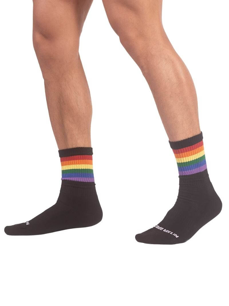A pair of mid-calf black gym socks with colorful pride stripes on the cuff, featuring the Barcode Berlin brand logo.