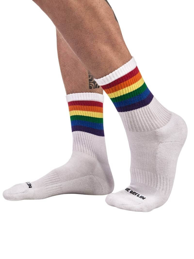 A pair of mid-calf white gym socks with colorful pride stripes on the cuff, featuring the Barcode Berlin brand logo.