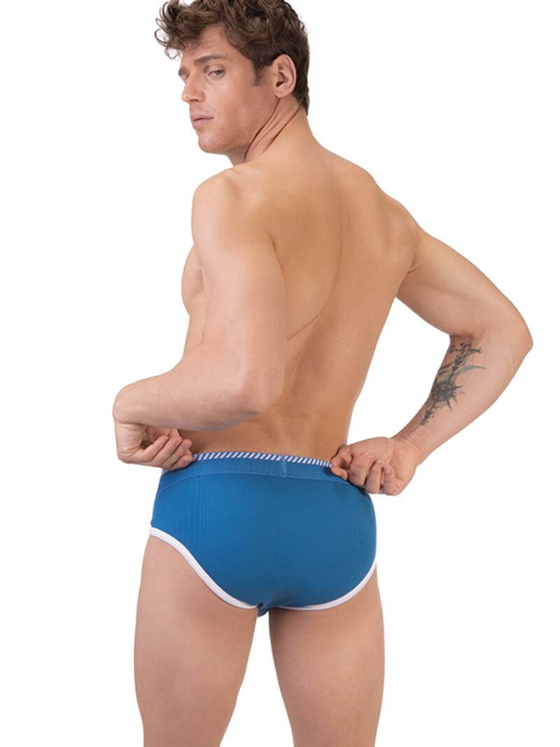 A man wearing a blue Barcode Berlin brief with white trims and a brand logo on the waistband.
