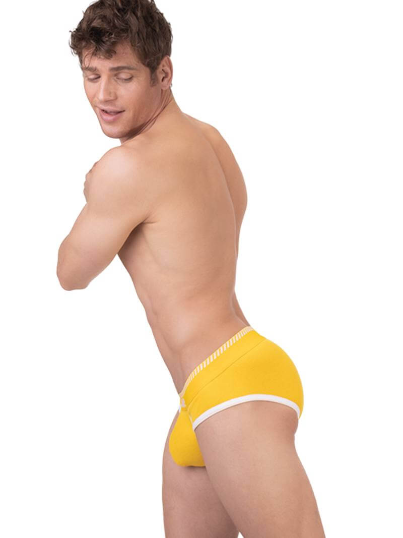 A man wearing a yellow Barcode Berlin brief with white trims and a brand logo on the waistband.