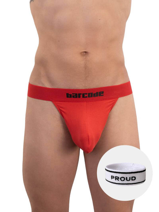 A red backless thong with Barcode branding on the waistband, featuring an elastic c-ring with 'Proud' lettering. The product is modeled by a male, showcasing the fit and design.
