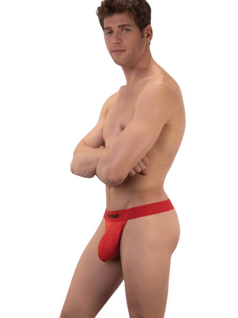 A black backless thong with Barcode branding on the waistband, featuring an elastic c-ring with 'Proud' lettering. The product is modeled by a male, showcasing the fit and design.