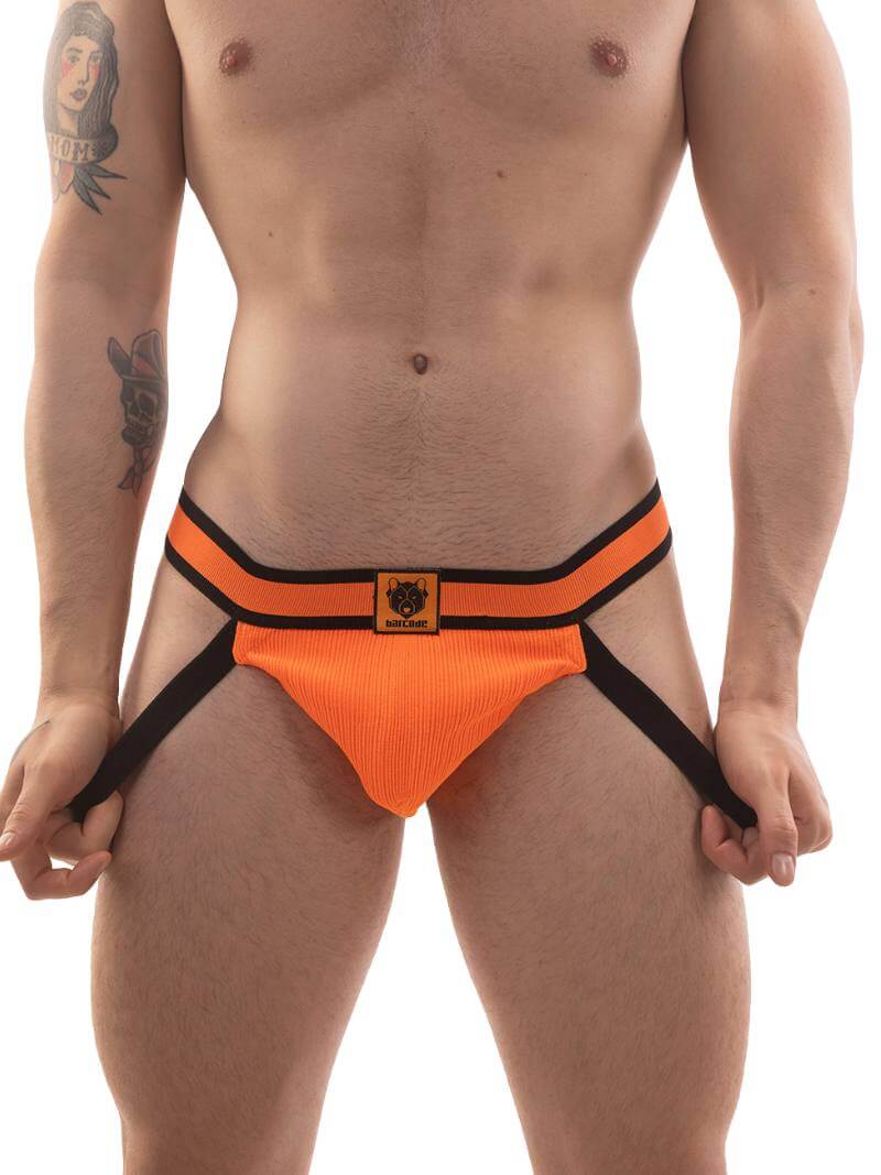 A model wearing a neon orange jockstrap with black straps and a striped waistband with the Barcode Berlin brand label.