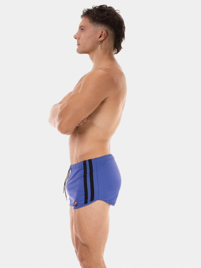 Man wearing blue swim shorts with a black stripe on a white background