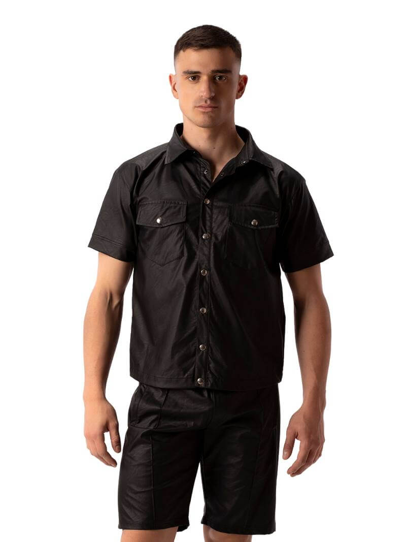 A man wearing a black faux leather shirt with metallic buttons and a collard neck, featuring short sleeves and a buttoned front.
