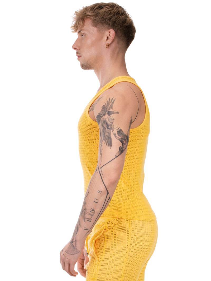 Person wearing a yellow sleeveless top and pants on a white background