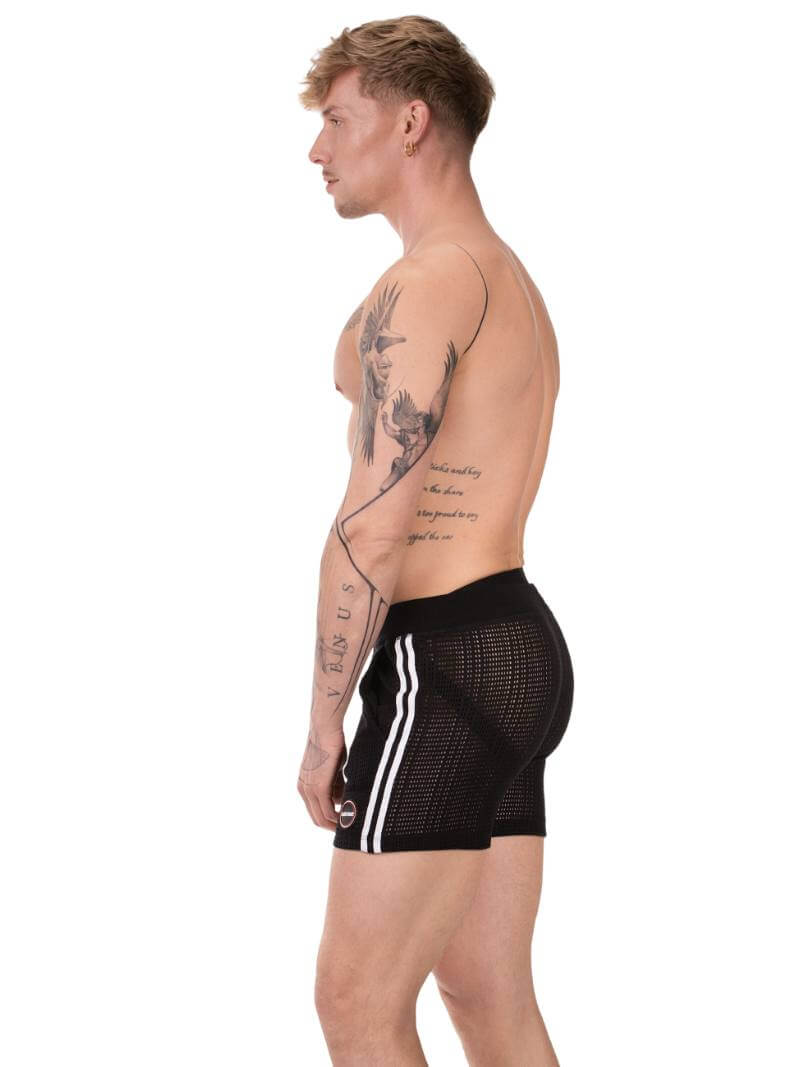 Person wearing black mesh shorts with white stripes on a white background