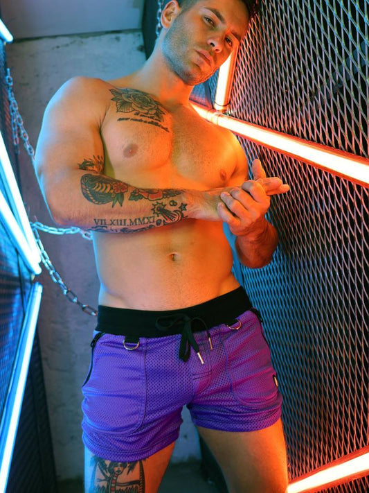 Man with tattoos holding a glowing red object against a textured wall.