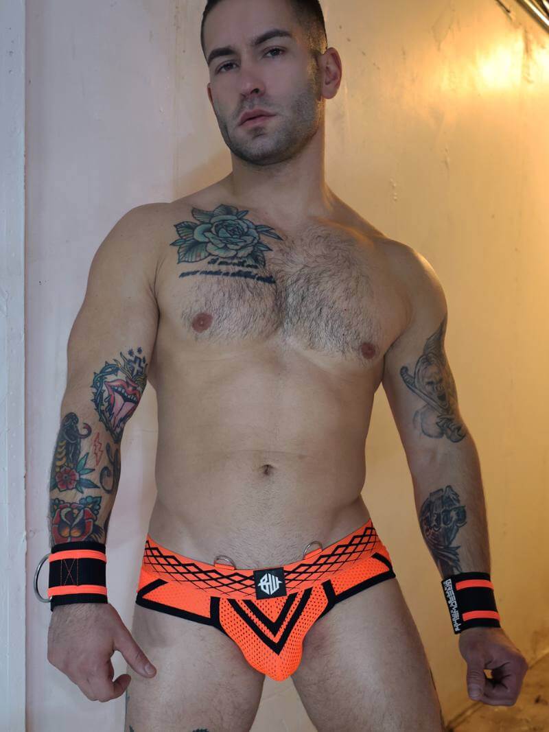 Man wearing bright orange underwear with black accents against a neutral background