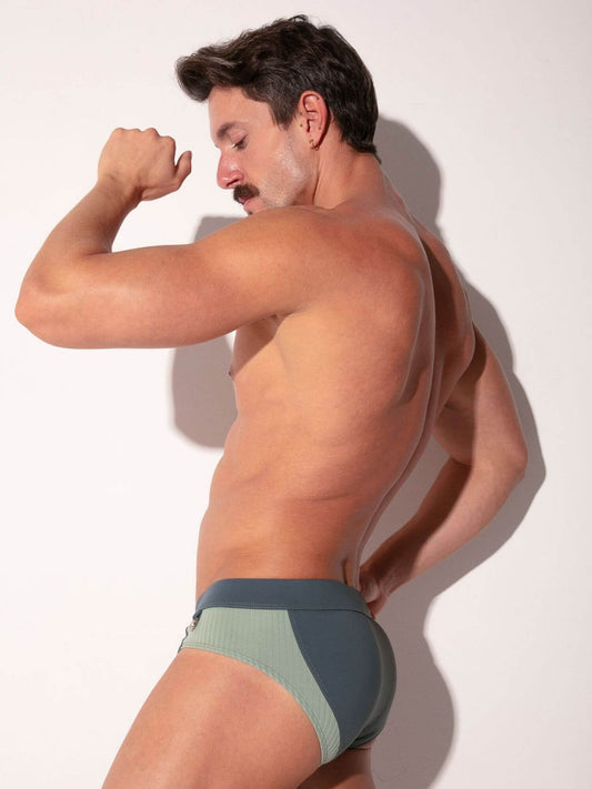 Man wearing a green and gray swimwear against a white background
