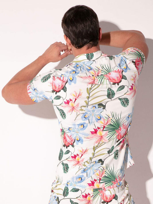 Person wearing a colorful floral shirt against a plain background
