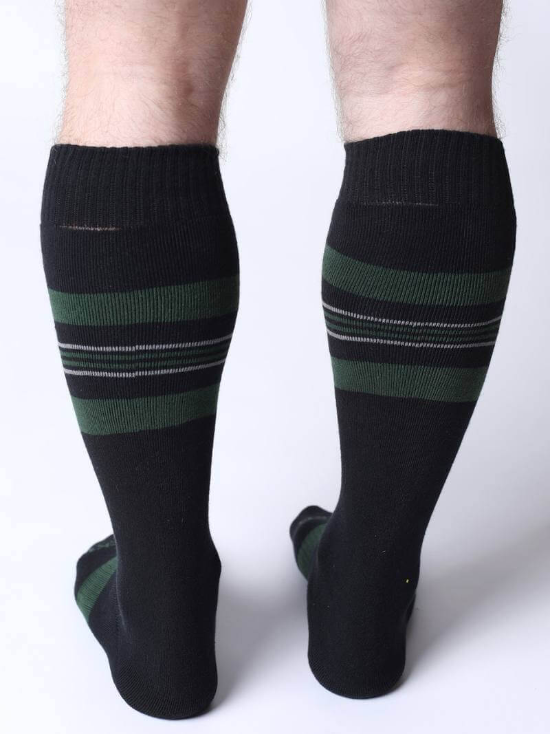 Black knee-high socks with green stripes worn by a person on a white background