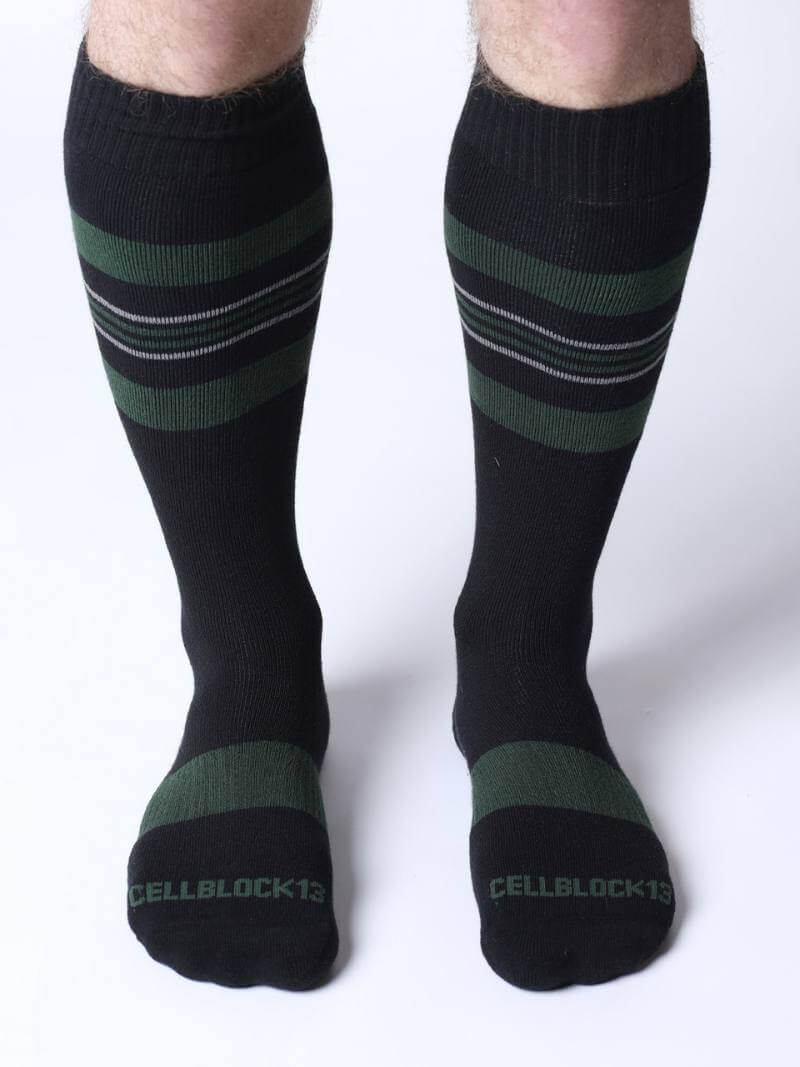 Black knee-high socks with green stripes worn by a person on a white background
