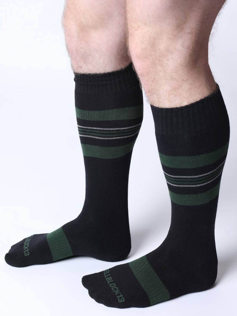 Black knee-high socks with green stripes worn by a person on a white background