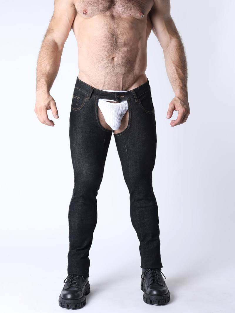 Man wearing black jeans with cut-out design and white underwear on a white background