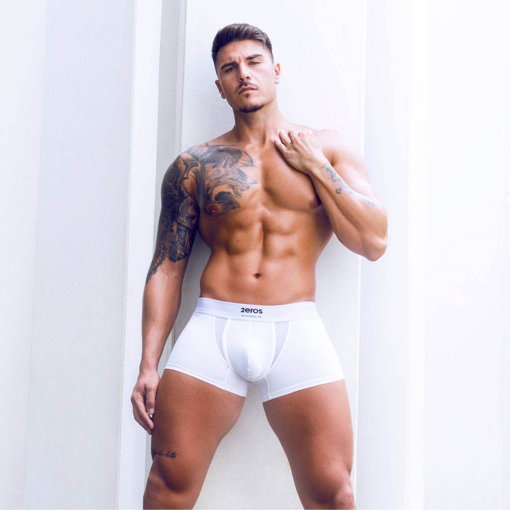 Man wearing white underwear with '2eros' brand logo against a light background