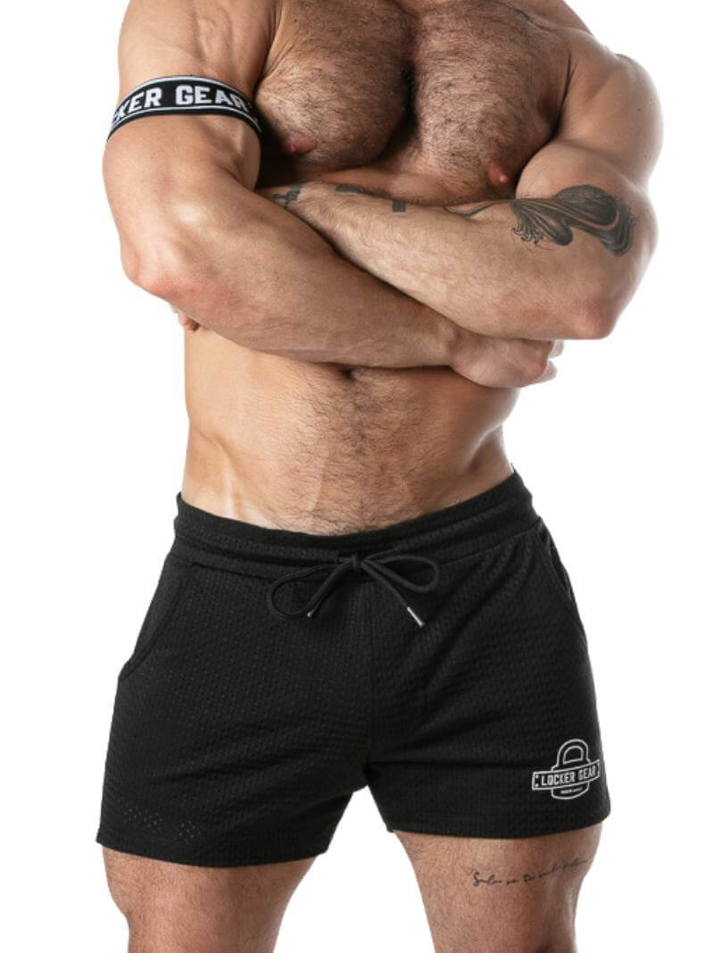 Gay guy wearing black athletic shorts with visible branding on a white background