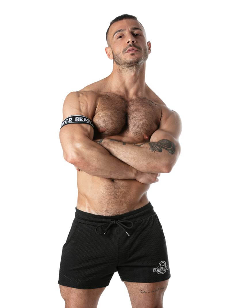 Muscular man wearing black shorts with brand logo on a white background