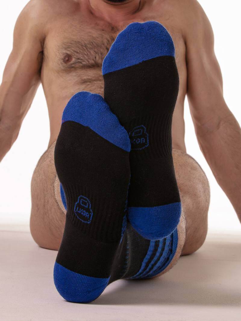 Black and blue socks being worn by a person on a white background